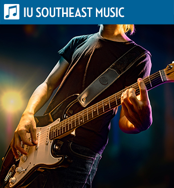 Person playing an electric guitar on stage with colorful spotlights.